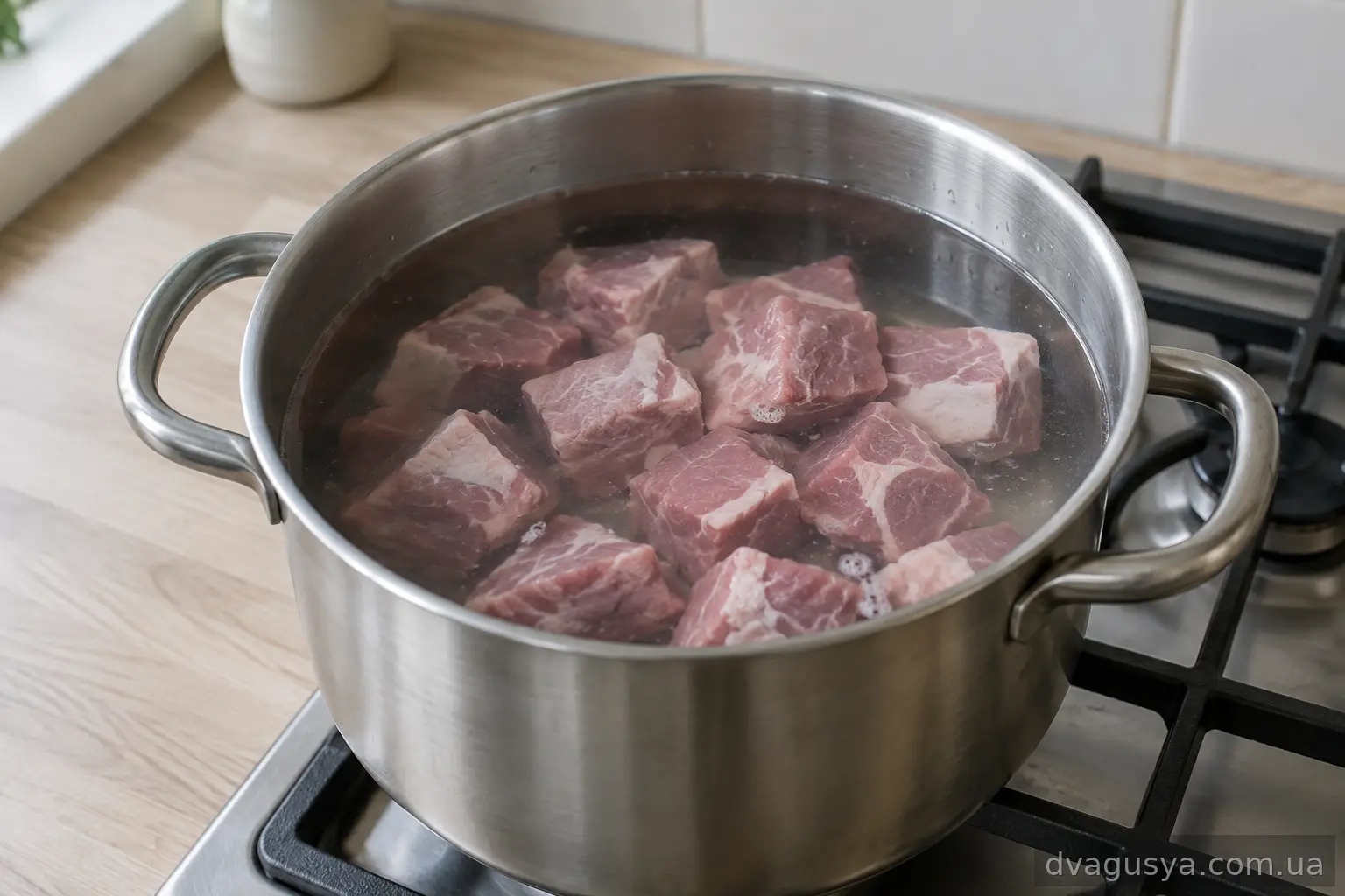 Свинина нарізана шматочками у каструлі із водою