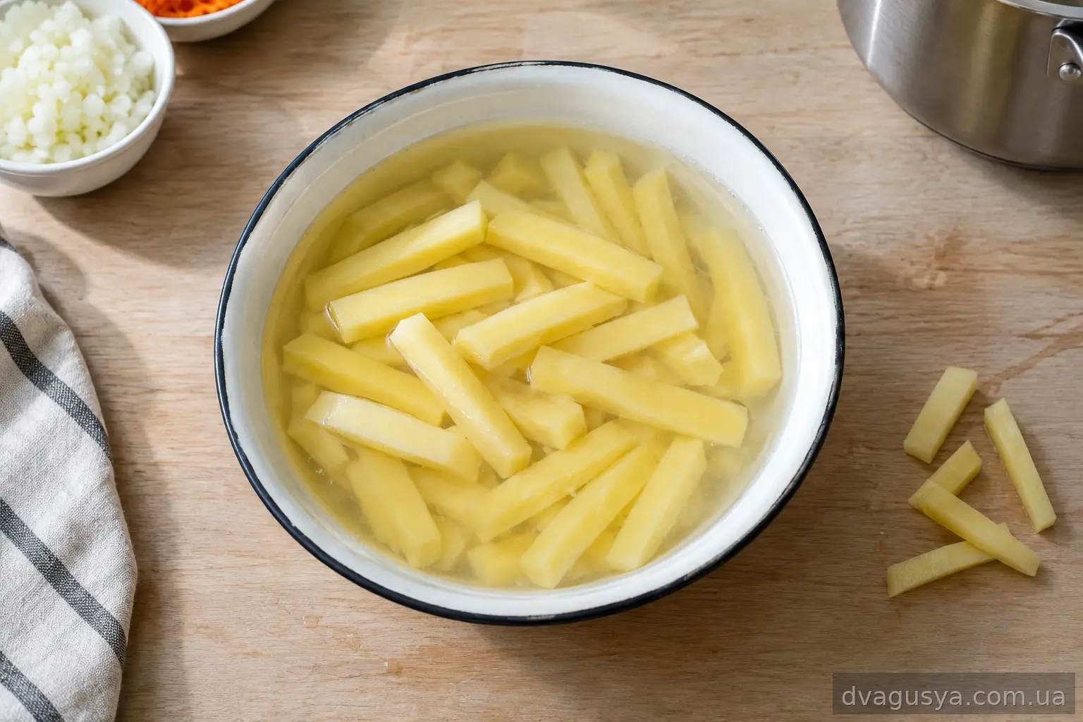 Картопля, нарізана брусками, у мисці з водою