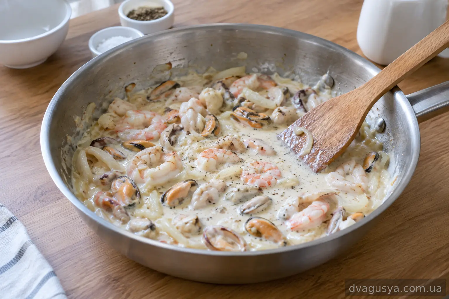 Вливання вершків до морепродуктів у сковороді